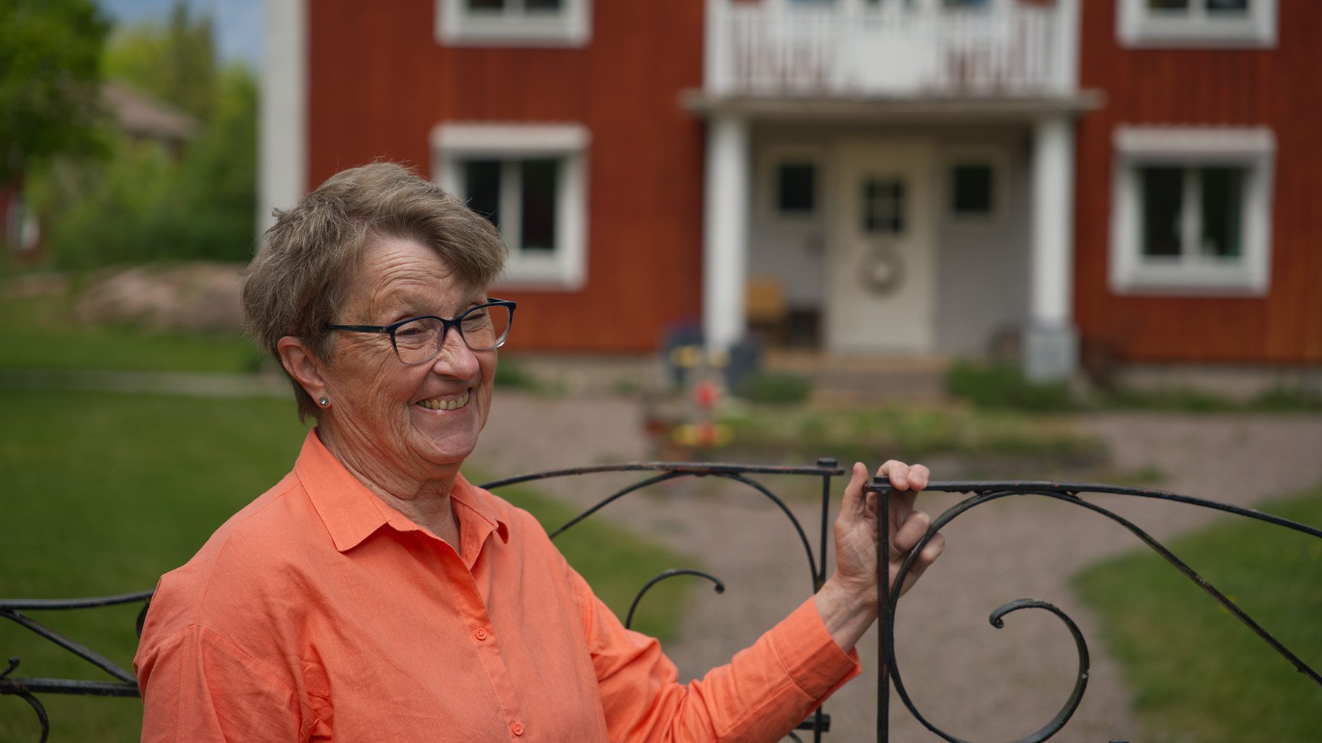 Färgbild på kvinna framför grind.