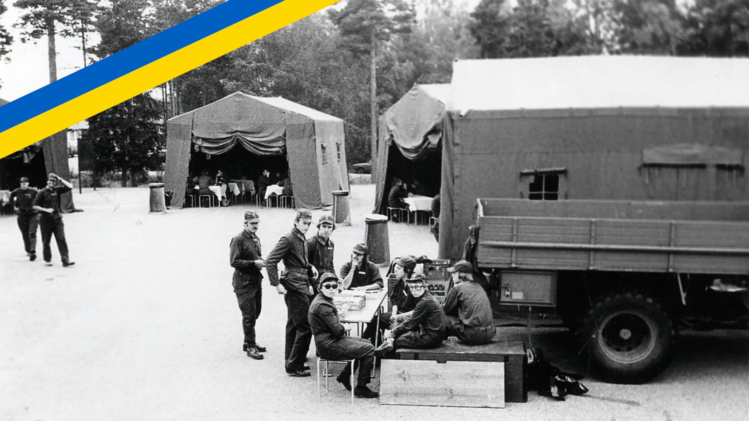 Svartvit fotografi på AM-budkavleorientering, 1977. Diverse tält och lastbilar.
